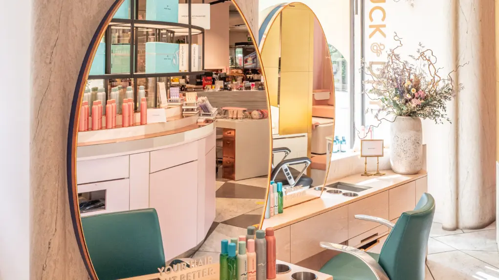 A beauty salon with a dressing table and mirror with a green chair