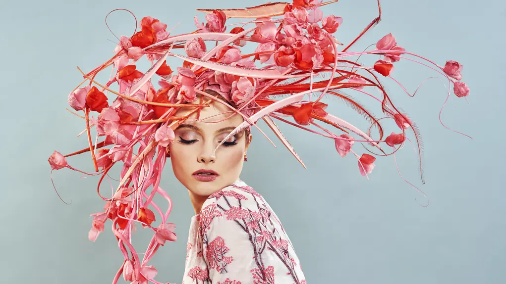 A woman wearing a huge pink hat covered in pink flowers