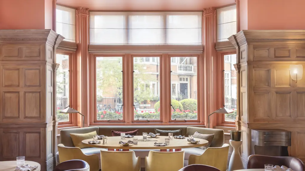 A huge bay window with a dining table with yellow-backed chairs
