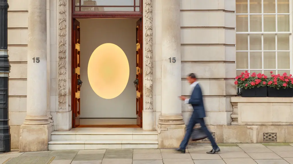 Man walking past a building with a large door with columns flanking it