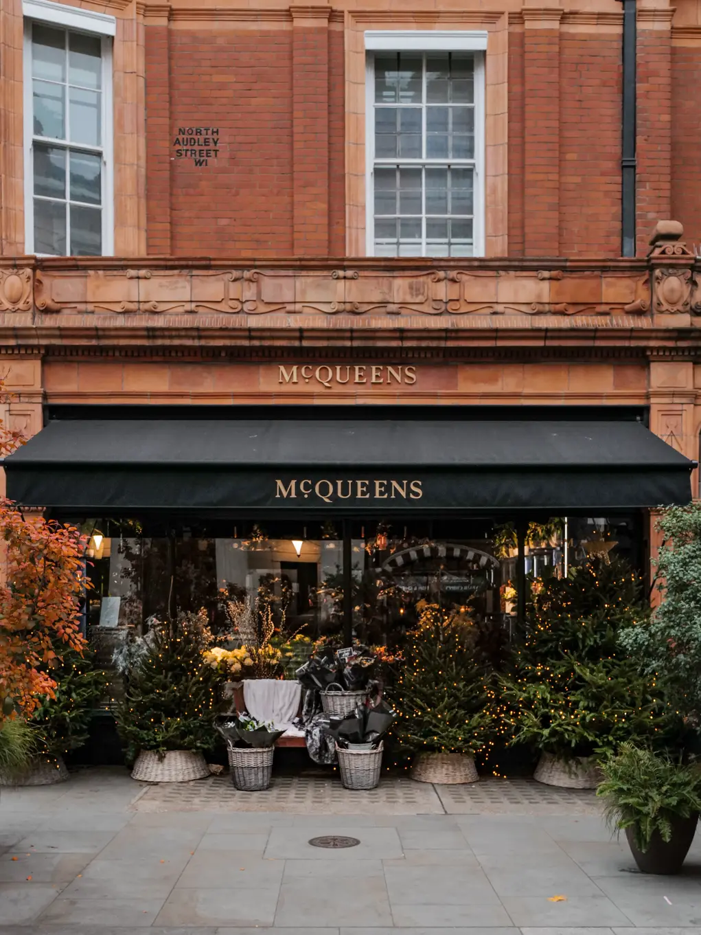 McQueens storefront on Brook Street Mayfair, decorated with seasonal flowers and lights