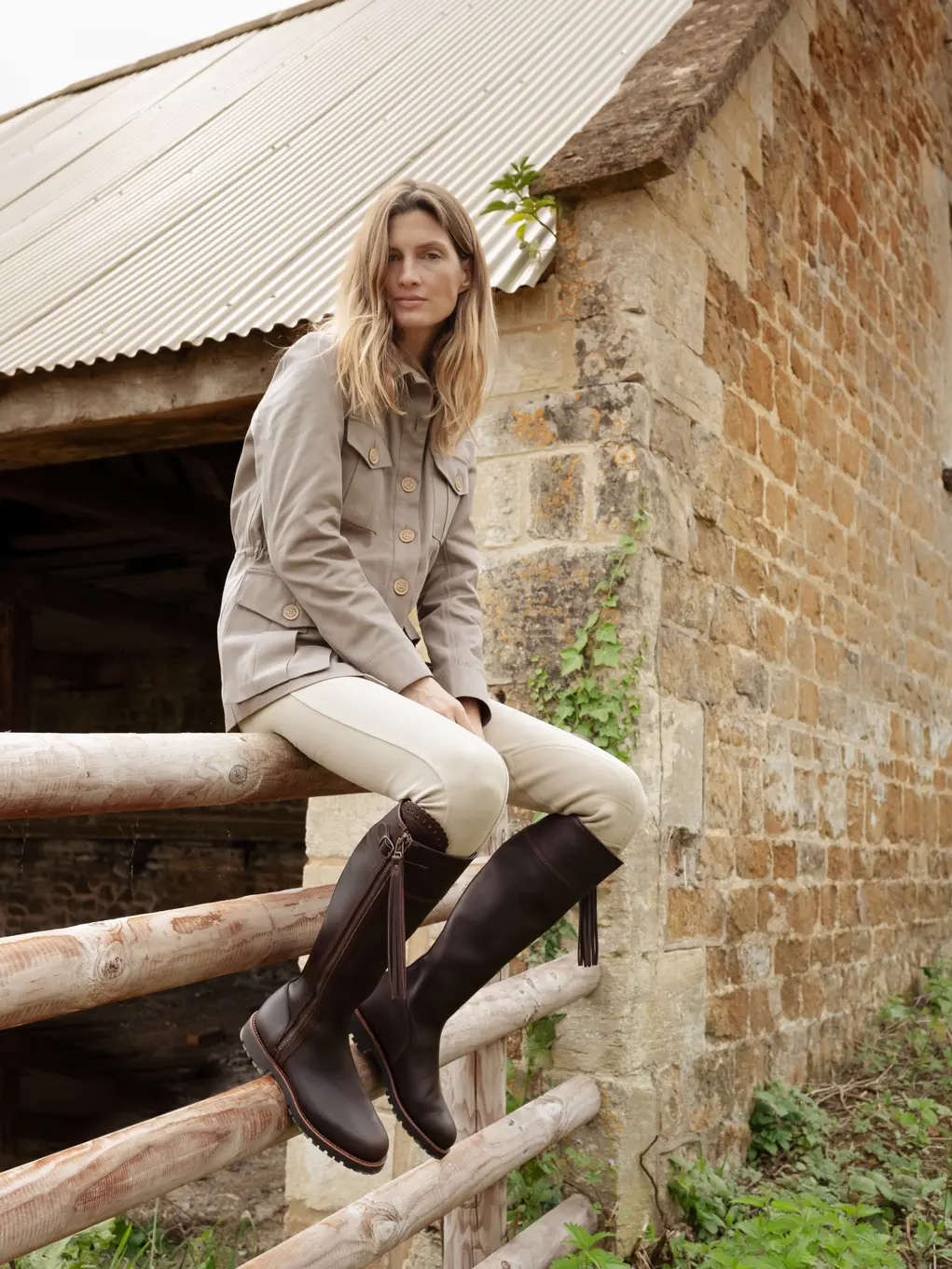 Lady with riding boots on sitting on a fence
