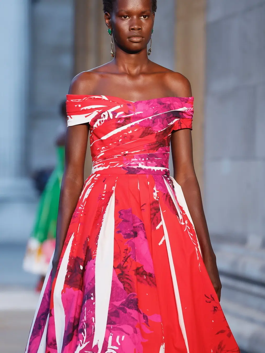 A woman wearing a pink, purple and white off-the-shoulder long gown
