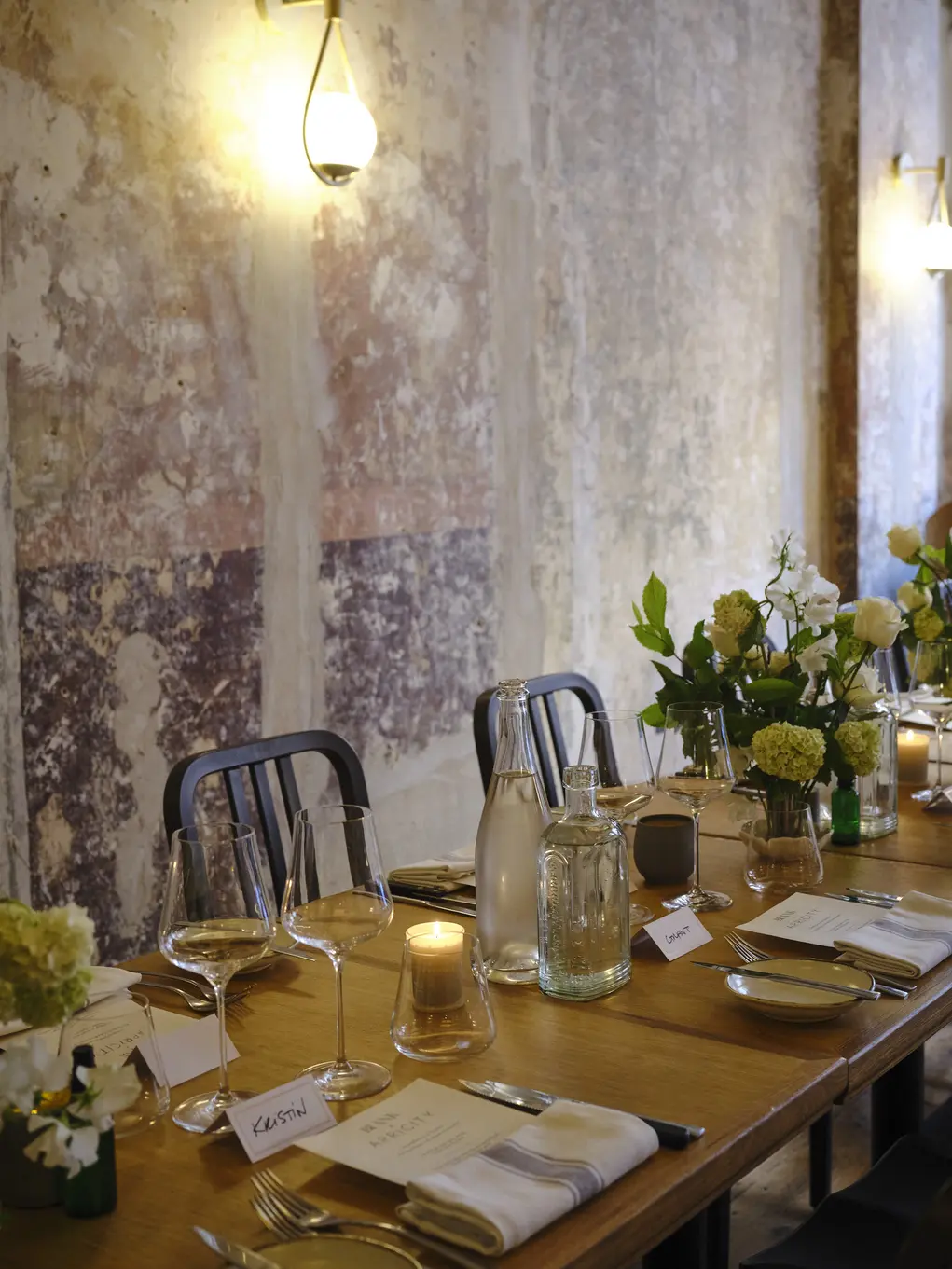 A dining table decorated for a wedding with white flowers, candles and name tags