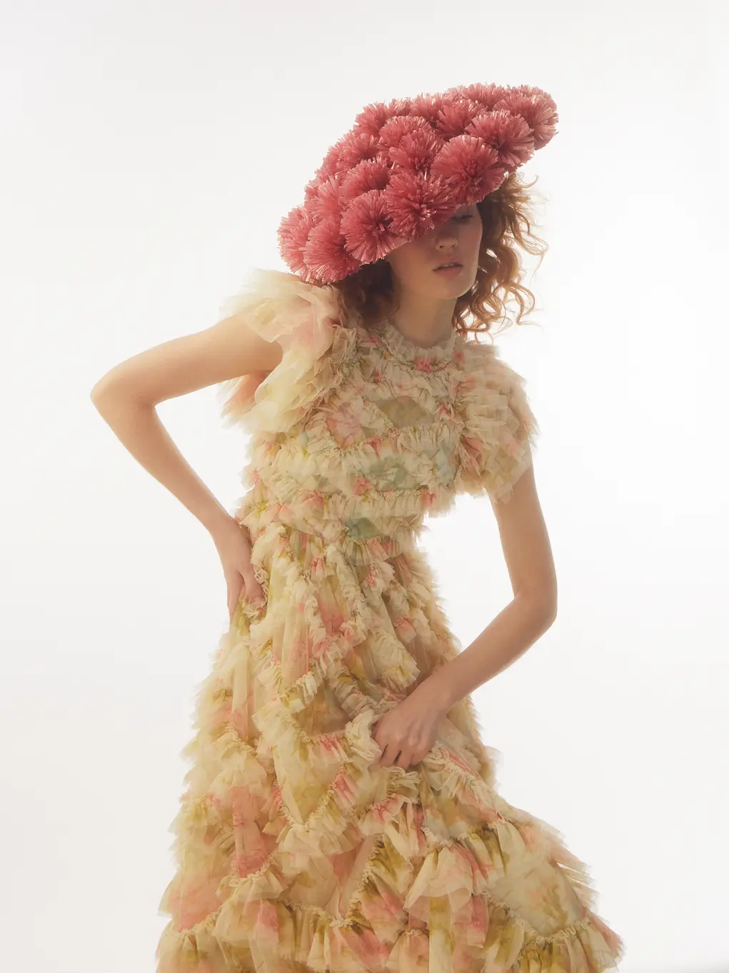 A woman wearing a large pink hat and a lacy dress 