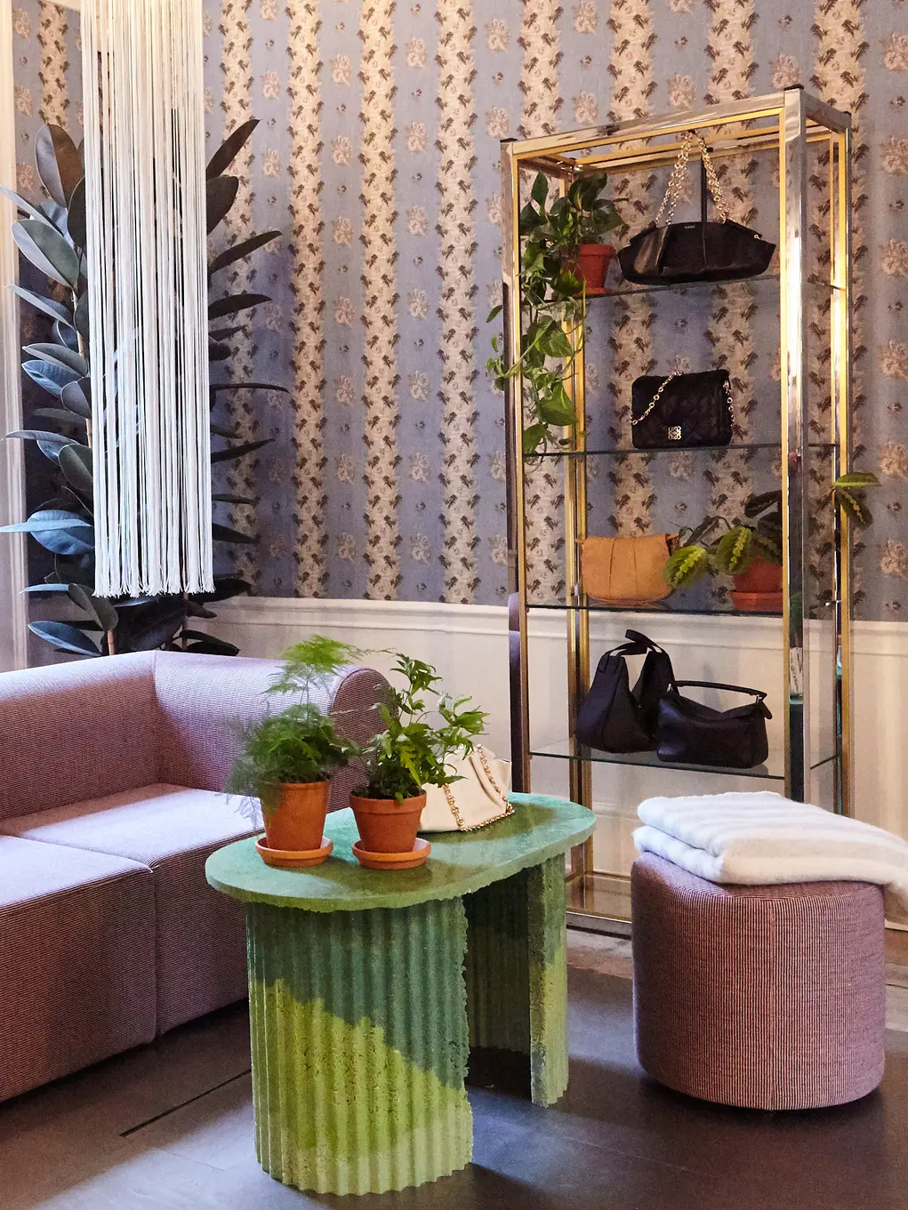 The inside of Browns with a pink sofa and gold shelves containing handbags