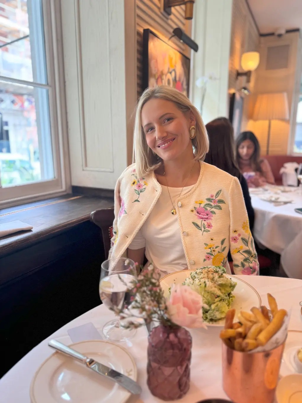 Laura-Ann sitting at a table in a restaurant wearing a white floral jacket
