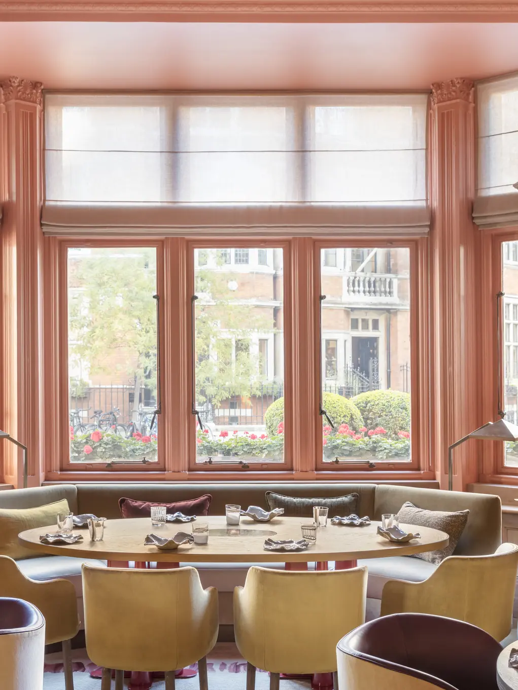 A huge bay window with a dining table with yellow-backed chairs