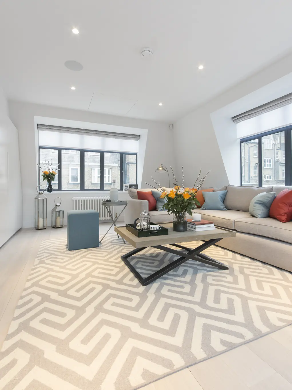 A large living room with windows on two walls and a large sofa
