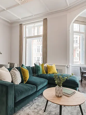 A living room with a teal corner sofa and dining table and chairs