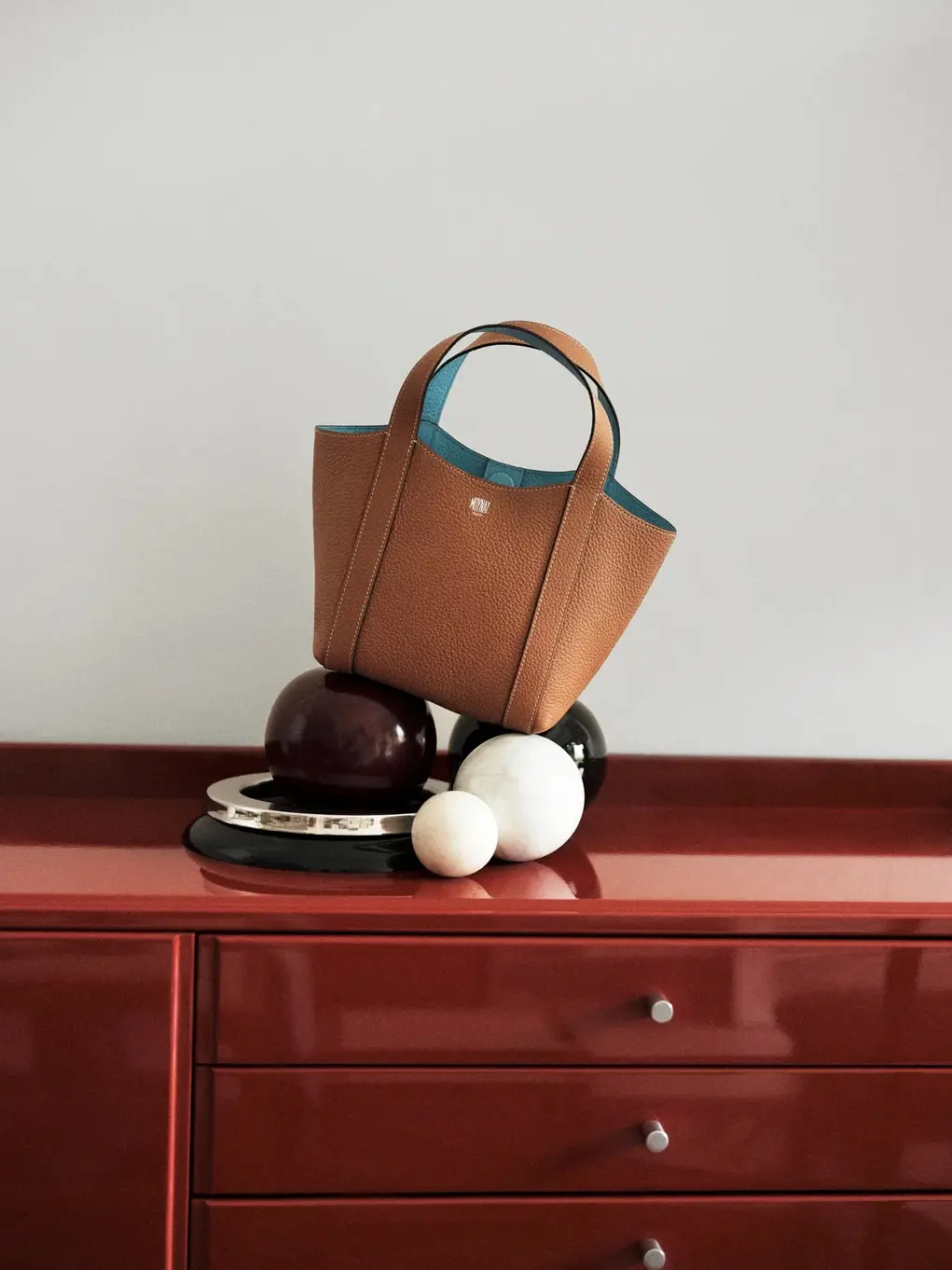 Brown Moynat handbag styled on a red table top
