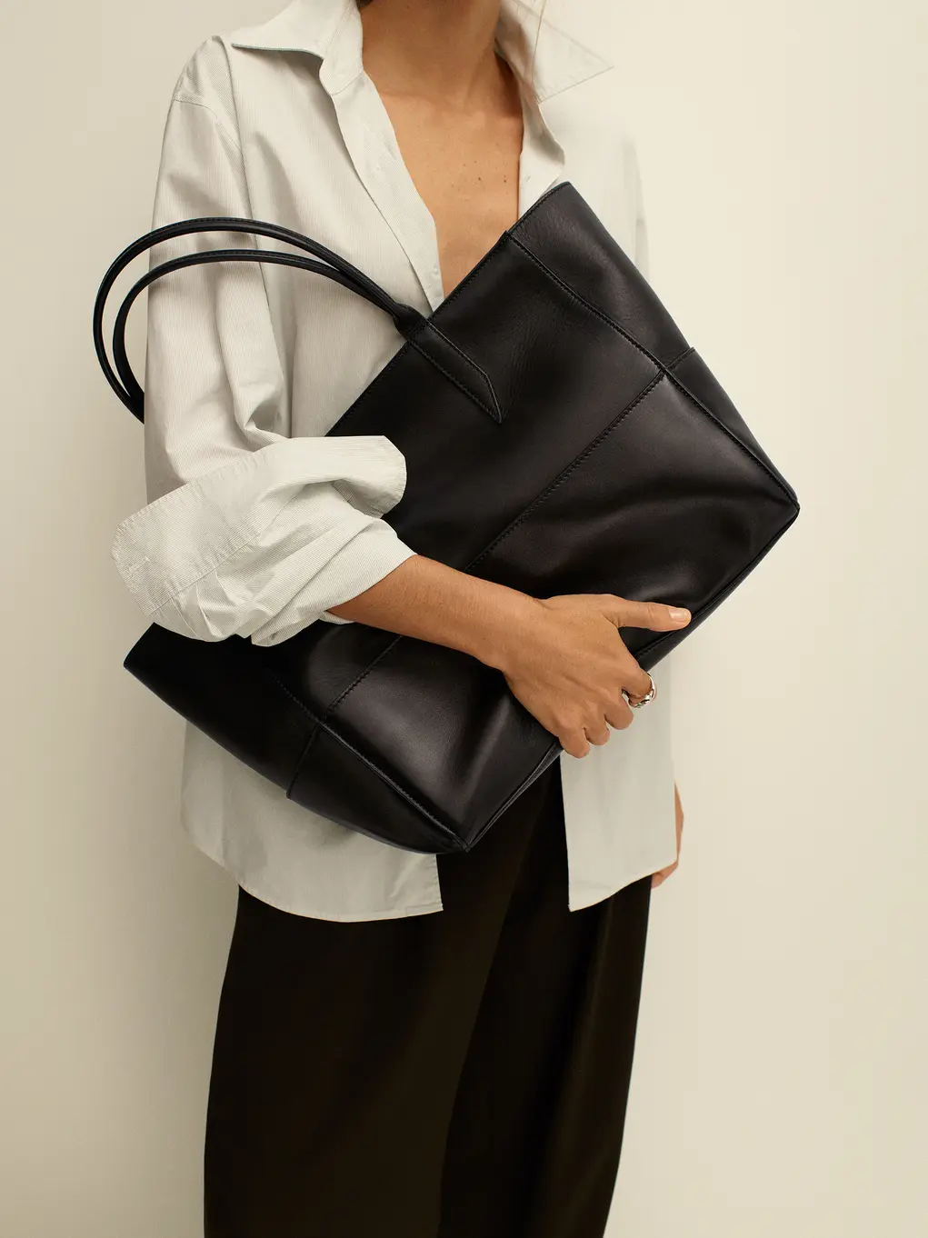 A woman in a white shirt holding a black bag