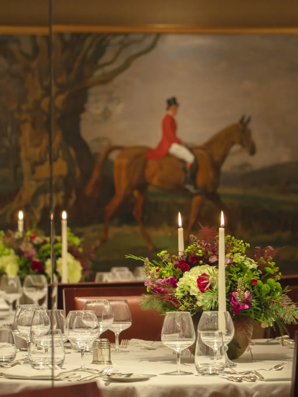 A table set for dinner with a picture of a horse rider in the background