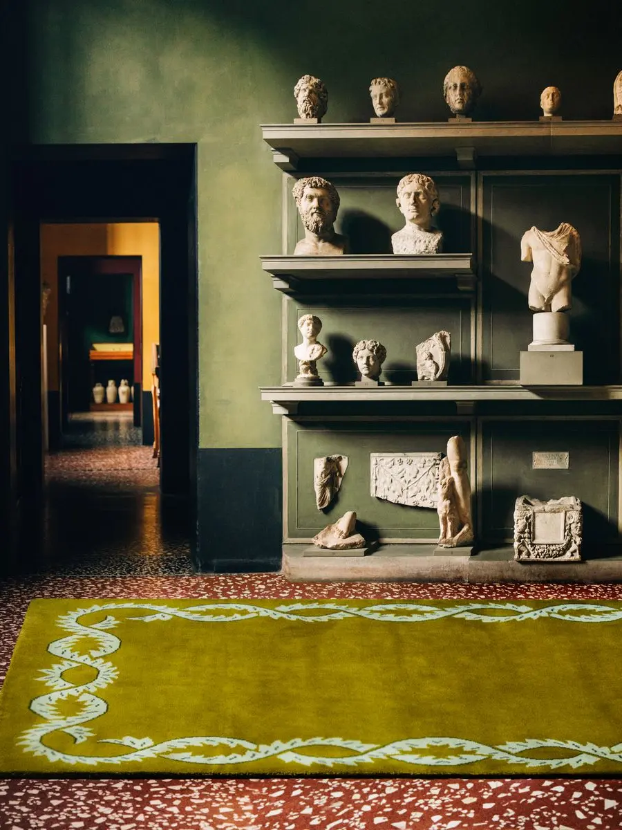 A room with a yellow rug and sculptures on shelves