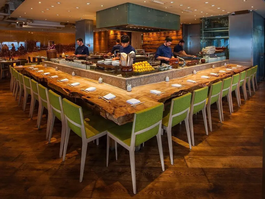 Seating area with green chairs inside Roka restaurant