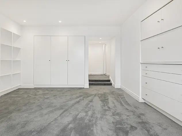 An empty room with fitted drawers and cupboards and wooden floors