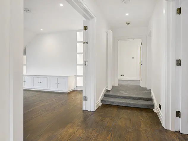 The hallway of an apartment with wooden floors and white walls