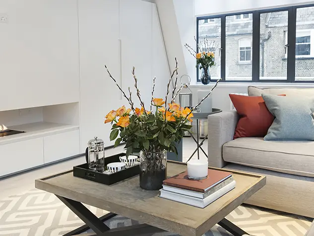 A living room with a sofa, coffee table and fire
