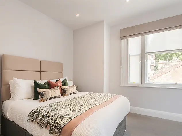 A bedroom with a double bed and bedside table with a lamp
