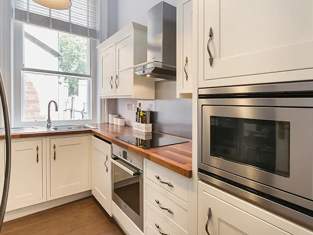 A kitchen with white cabinets and a microwave