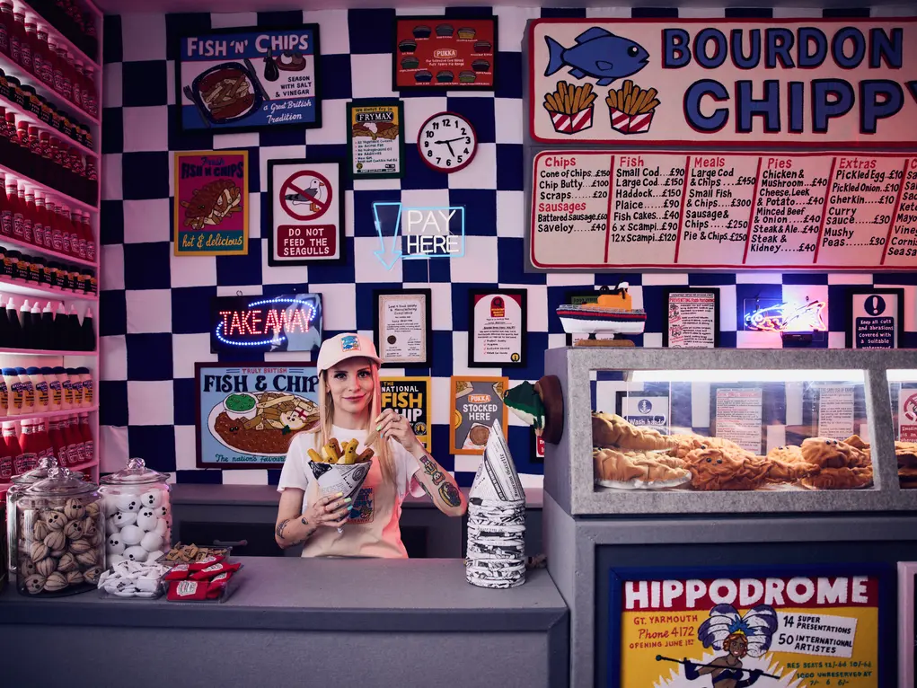 Artist Lucy Sparrow behind the counter of her fish and chip shop installation 