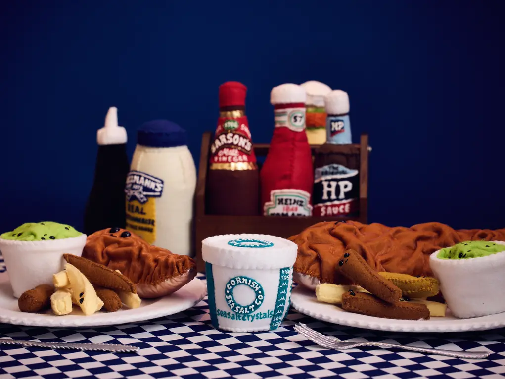 A table with condiments and plates of fish and chips